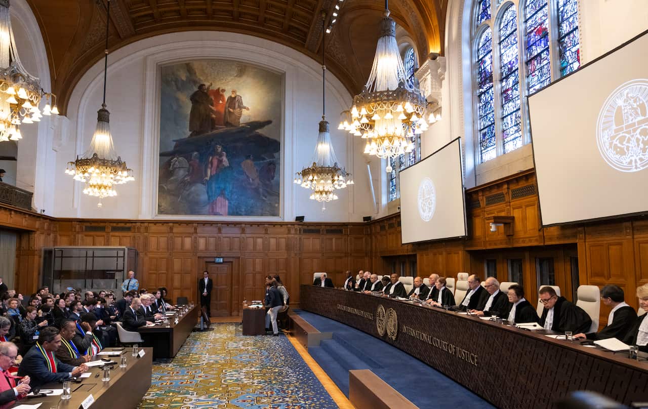 A group of people sitting at desks and podiums in the International Court of Justice.