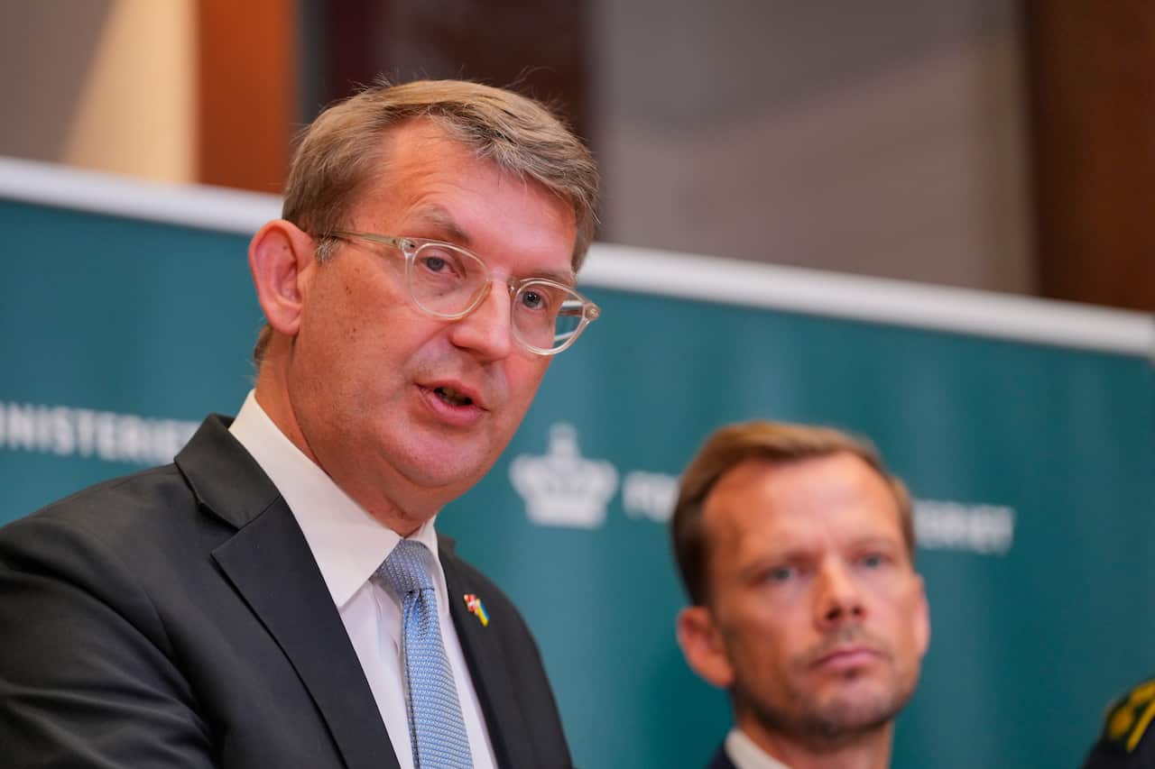A middle-aged man wearing glasses and a suit speaks at a press conference. 