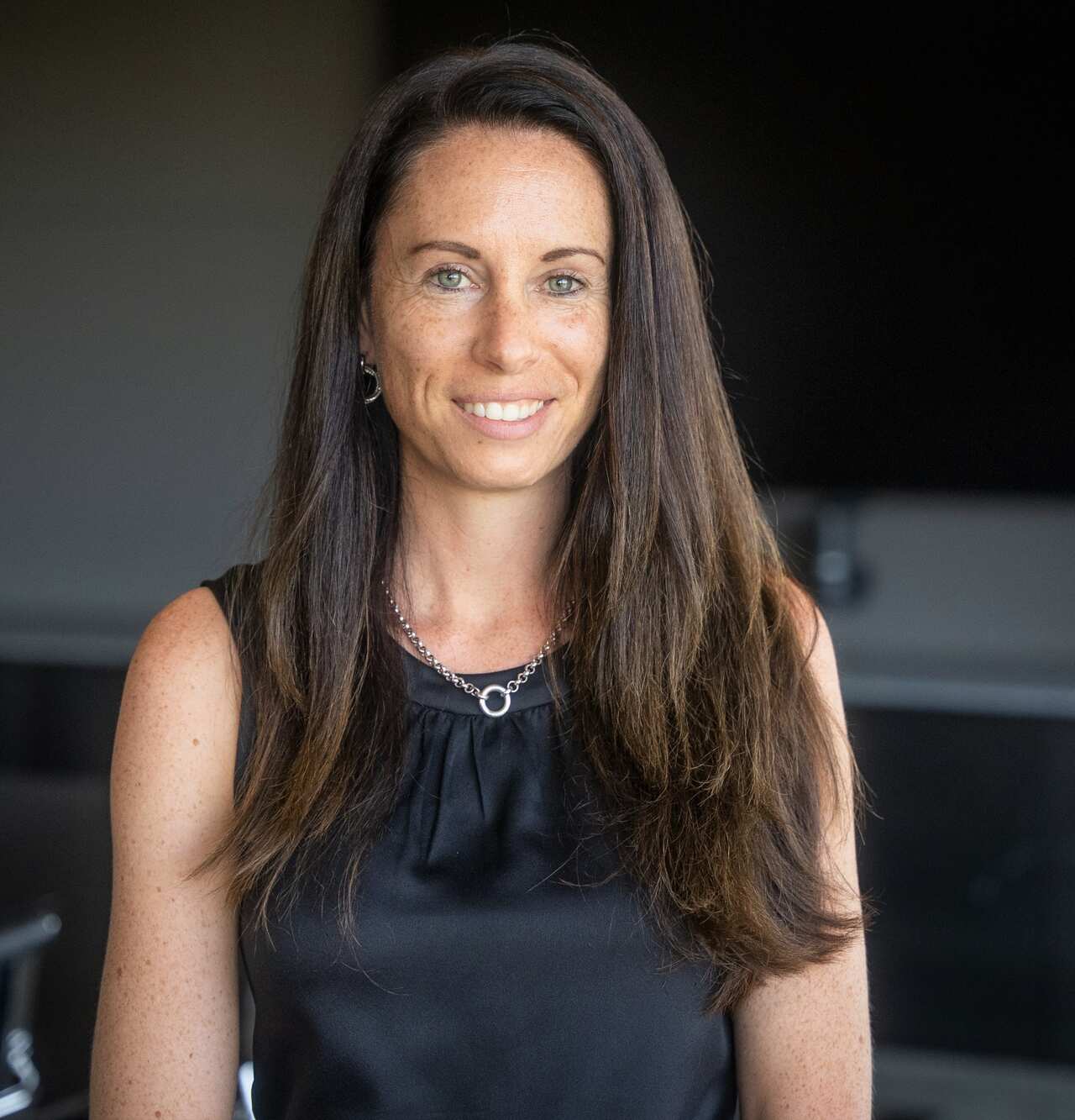 A woman with long black hair is smiling at the camera.