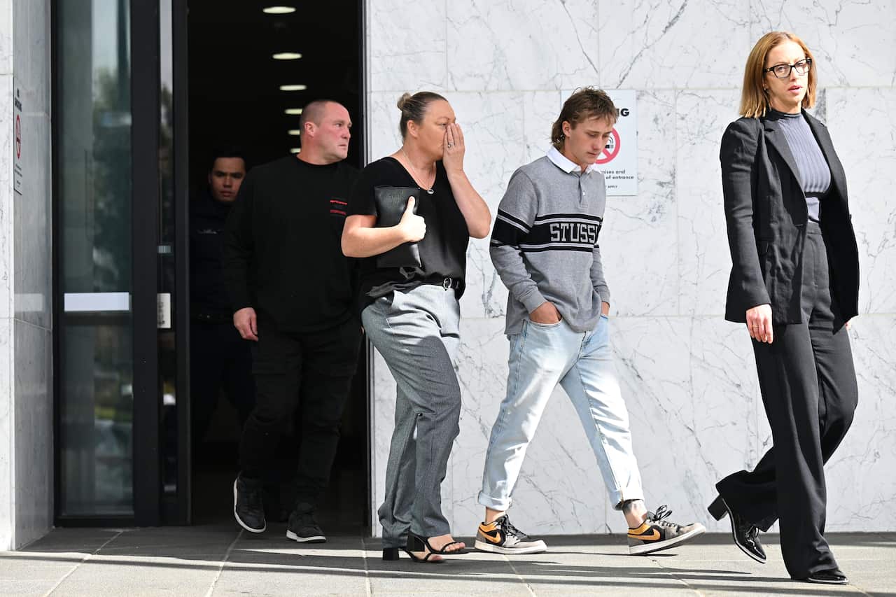 A family exit a court, appearing distressed.