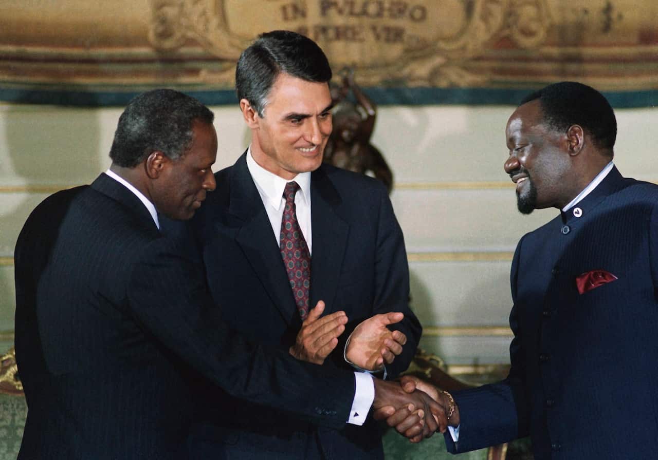 Angola's President Jose Eduardo dos Santos (left) greets UNITA leader Jonas Savimbi (right) as Portuguese Prime Minister Cavaco Silva (centre) looks on, during the signing of the peace agreement for Angola at Necessidades Palace in Lisbon on 31 May 1991.