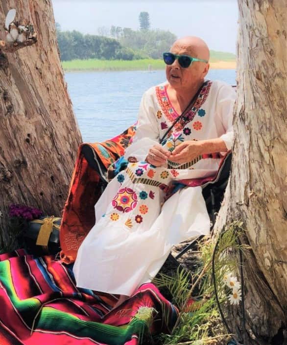 A woman sits in a tree after losing her hair during chemotherapy treatment.