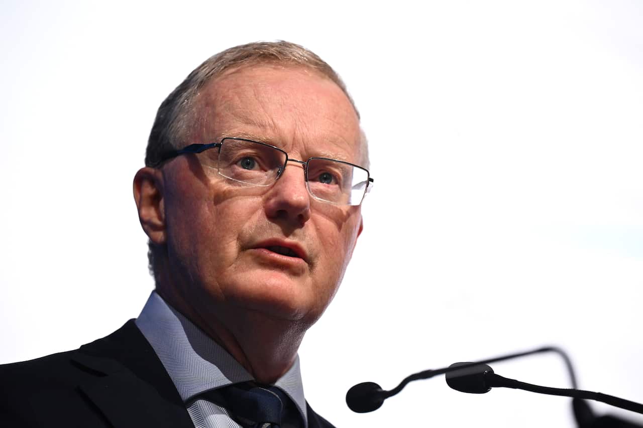 Philip Lowe wearing a suit and tie and speaking behind a microphone