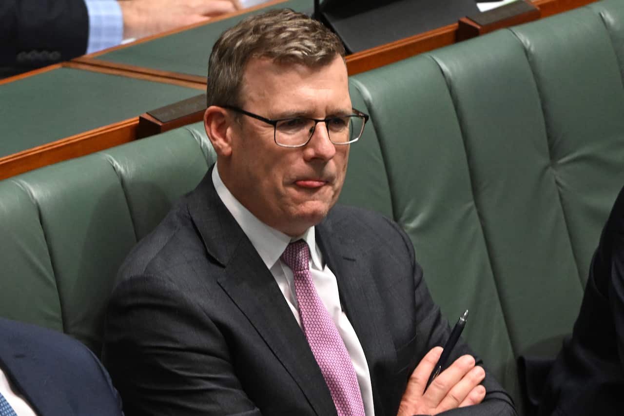 Man crosses arms as he holds a pen.