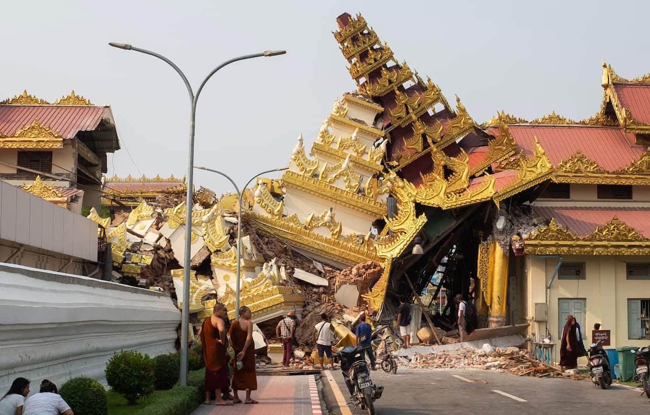 A crowd of people looking at a collapsed ornate gold temple