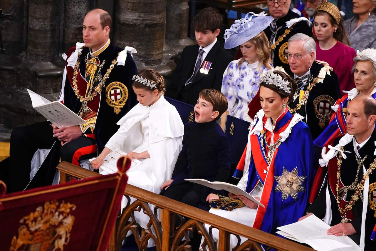 A group of royals in ornate clothing sitting at pews.