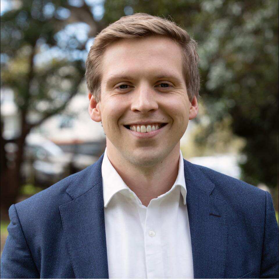 A man wearing a blue suit jacket smiling.