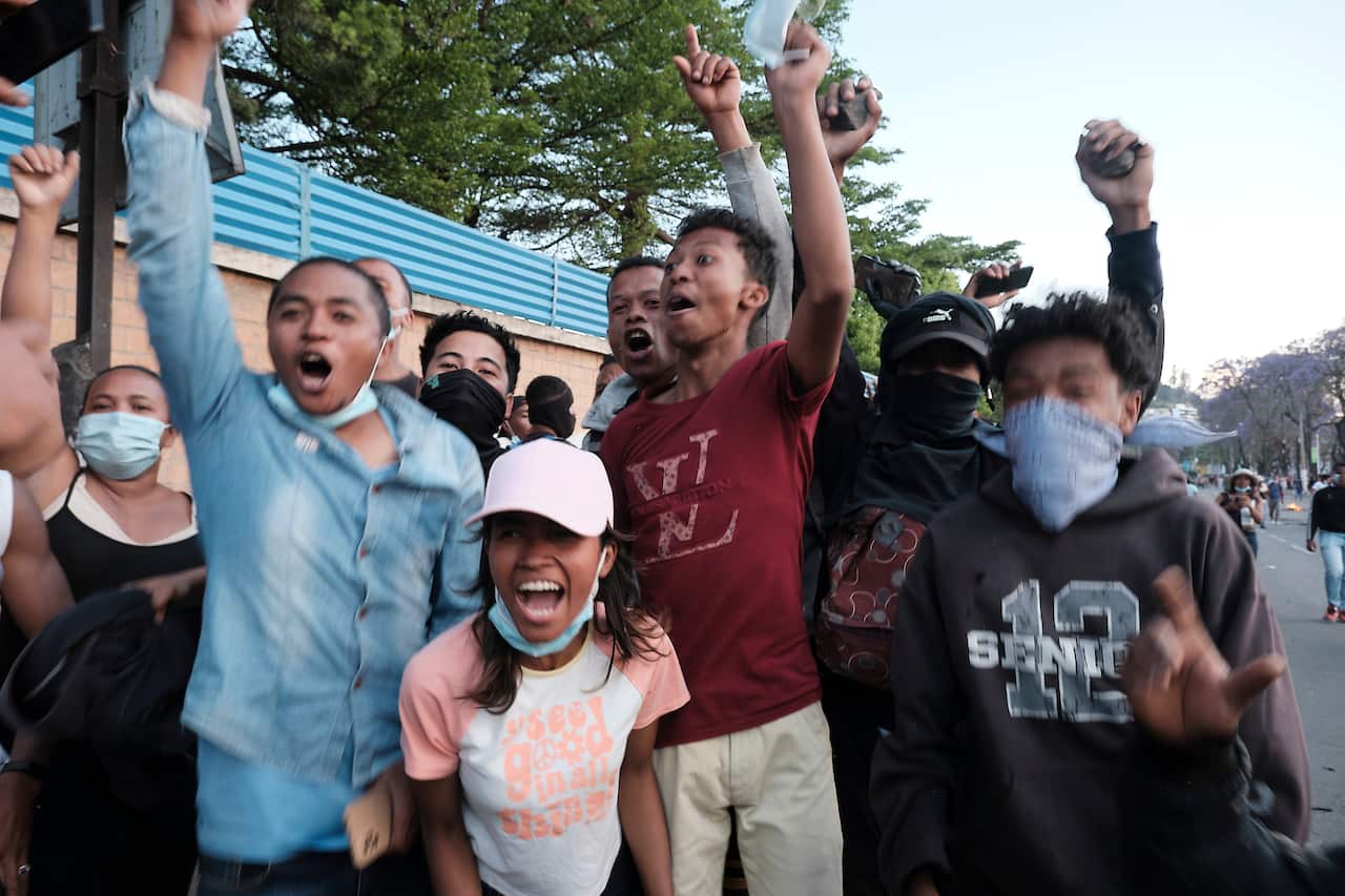 Activists take part in an anti-government protest, cheering and grinning.