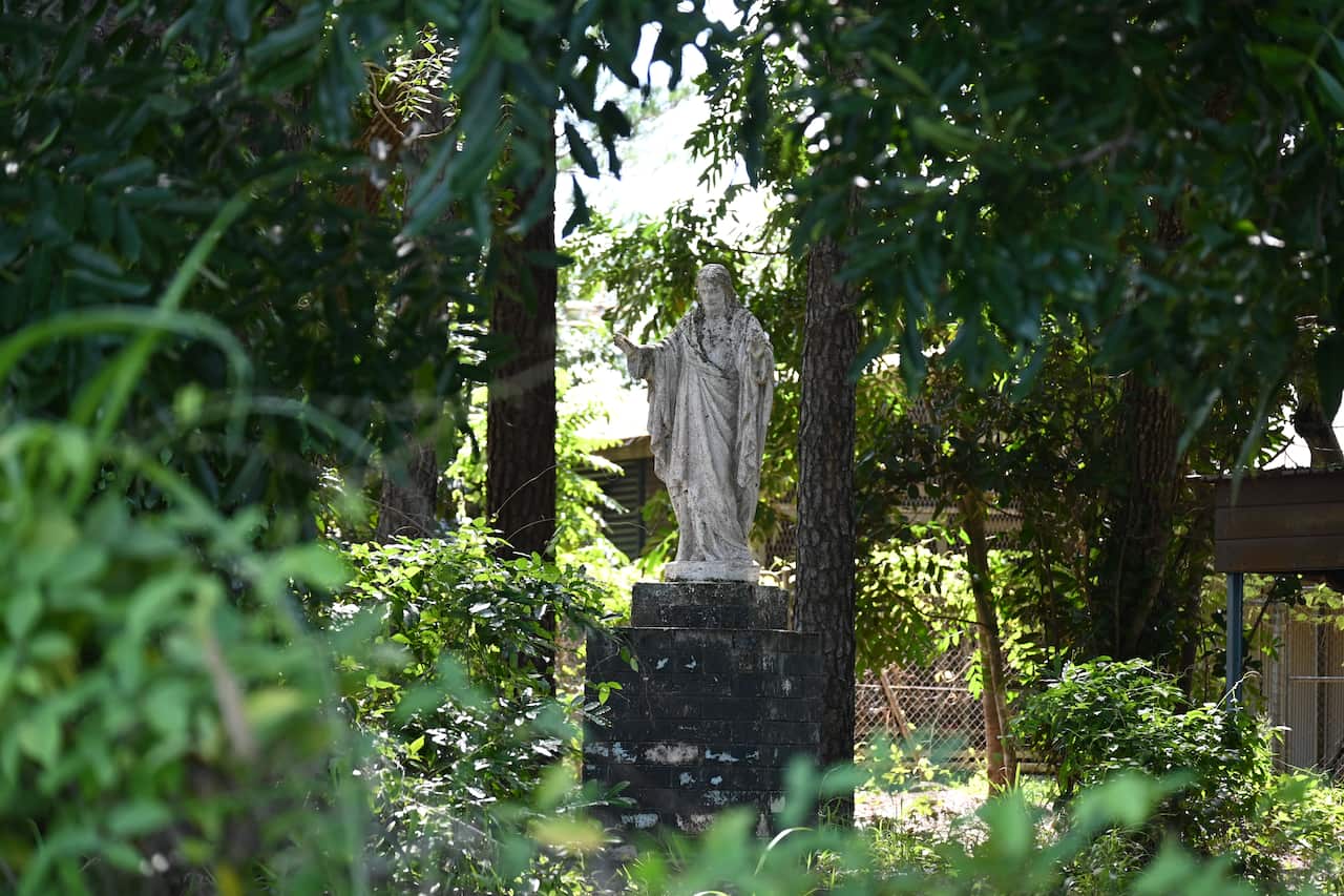 A statue of Jesus in an overgrown yard