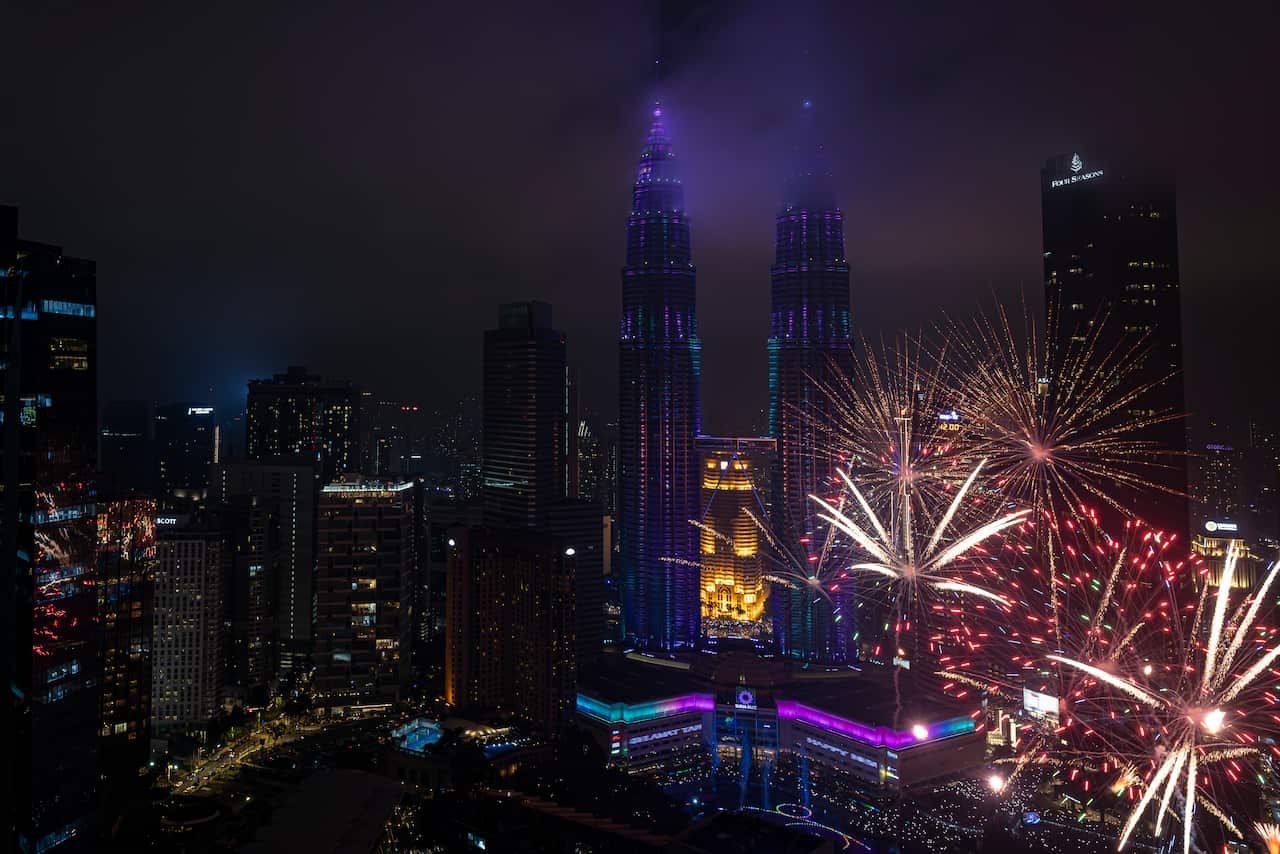 Fireworks over a colourfully-lit city.