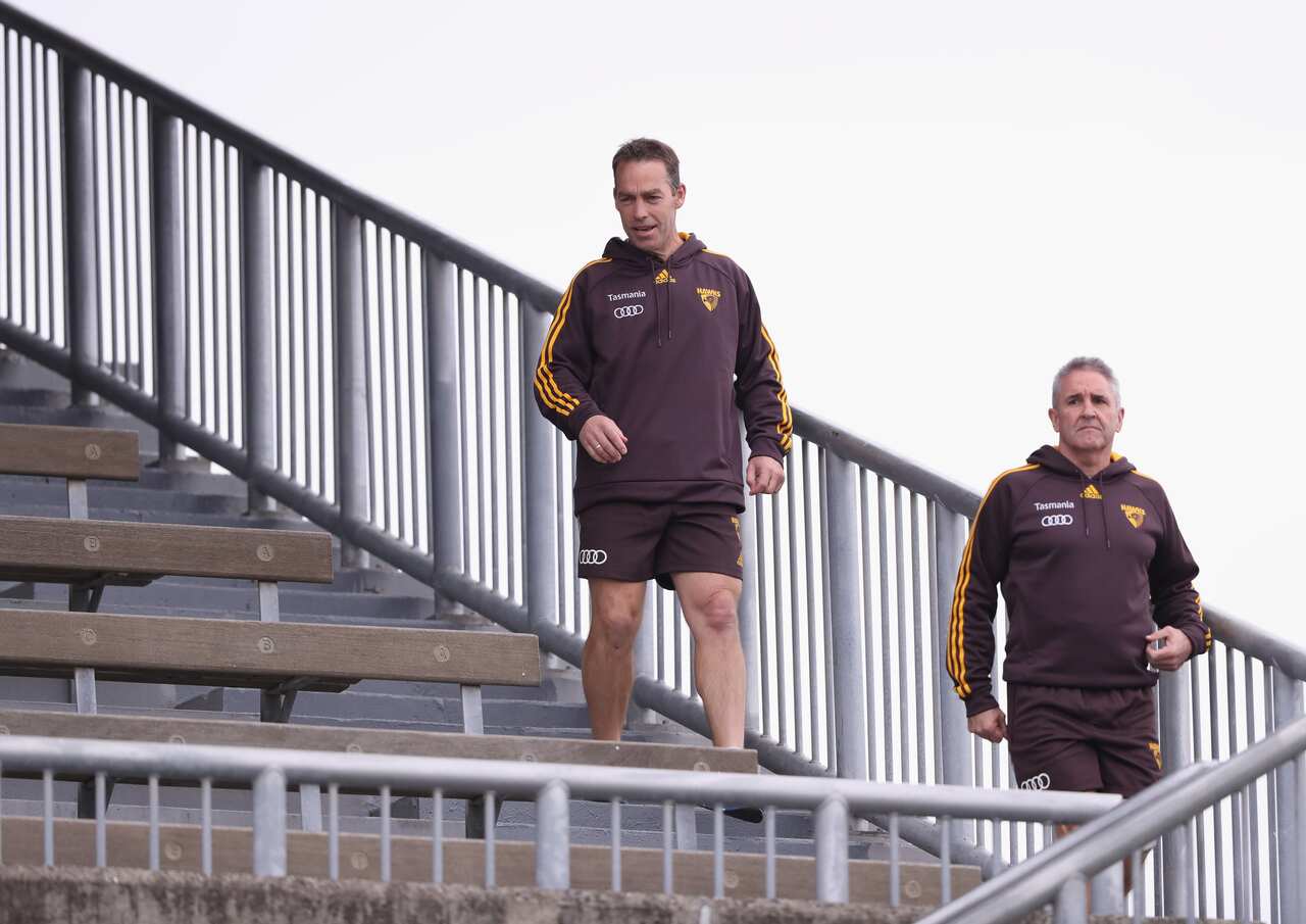 Alastair Clarkson and Chris Fagan in maroon hawks gear in the bleachers