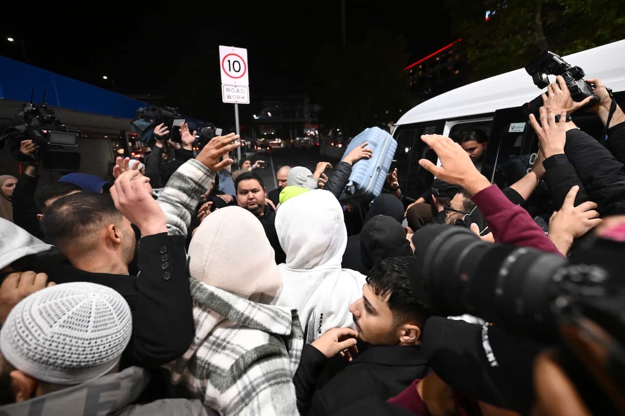 Three women move through a large crowd of people.