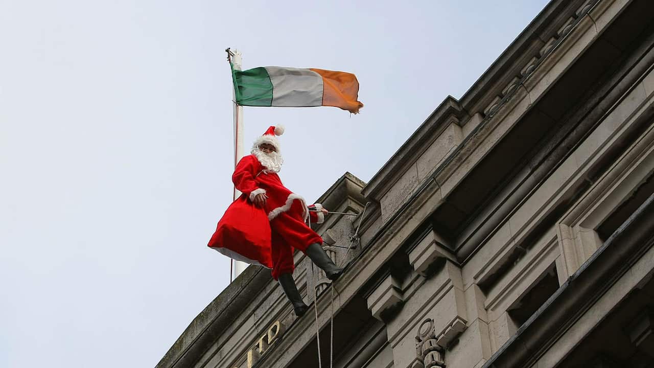 Santa scaling the side of a building with the Irish flag in the background.