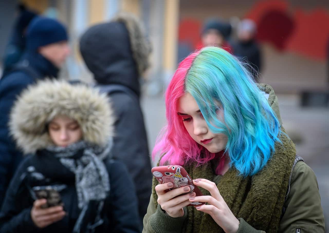 Young women looks at their mobile phones on a street in central Moscow on 26 February 2019. 