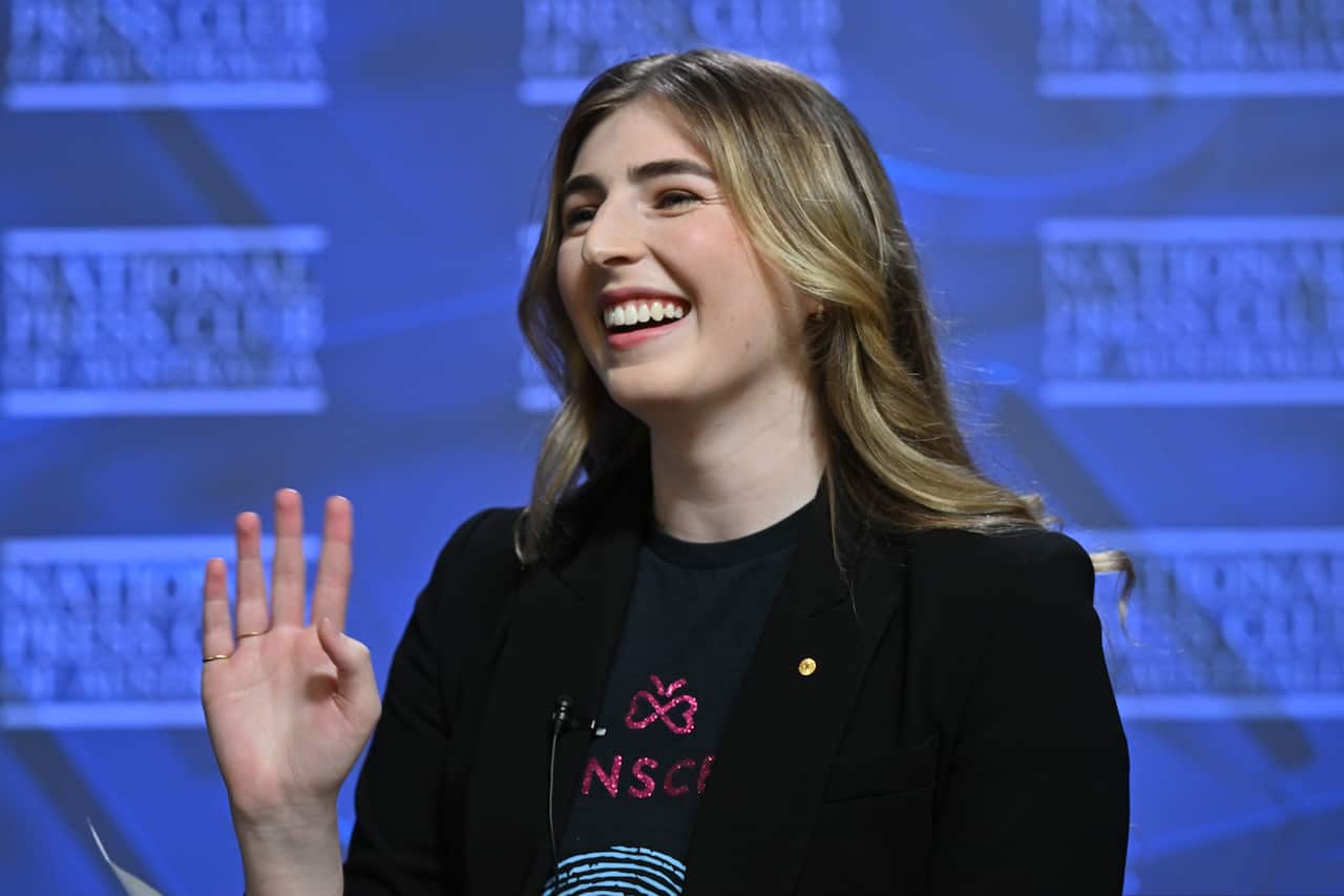 Woman smiles and waves.