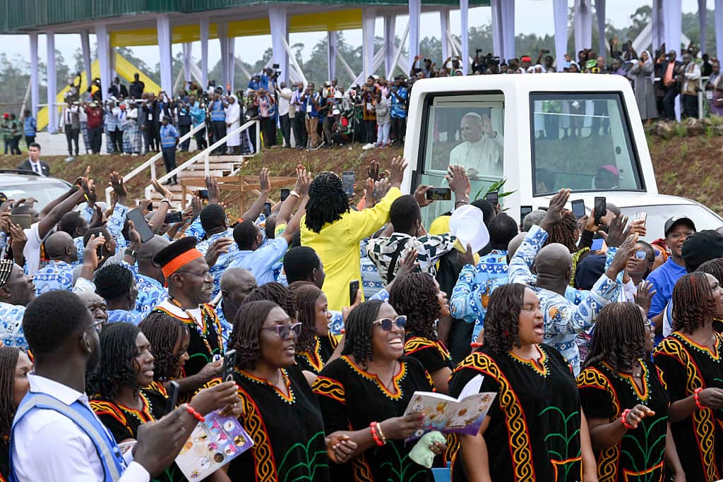  Pope Leo XIV waves to his faithful from his popemobile, which is surrounded by jubilant crowds of people.