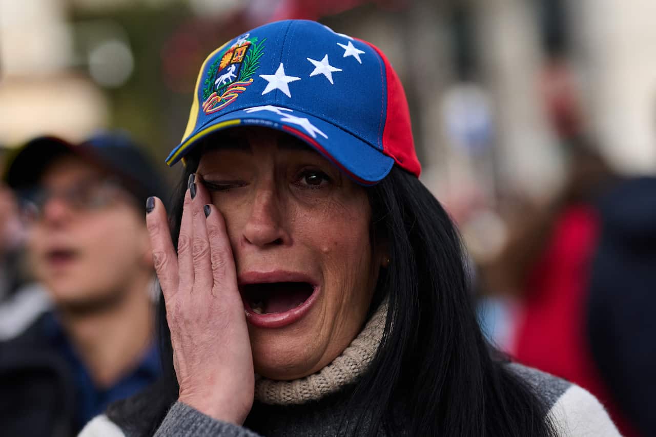 In Madrid, a Venezuelan wipes tears on her face 