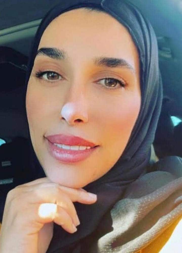 A woman wearing a hijab looking into a camera.