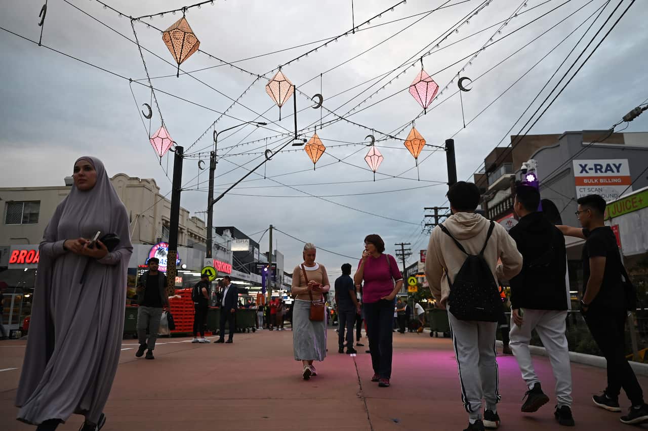 People walk through a street with decorations hung up. 