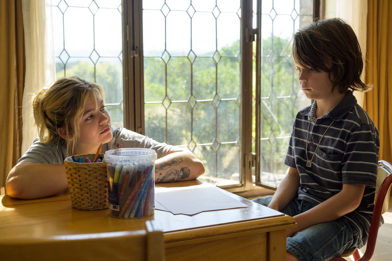 A young boy stares at a table with paper and colouring pens