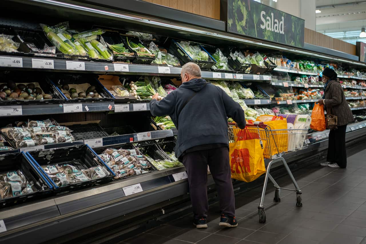Two shoppers browse the salad section of a supermarket