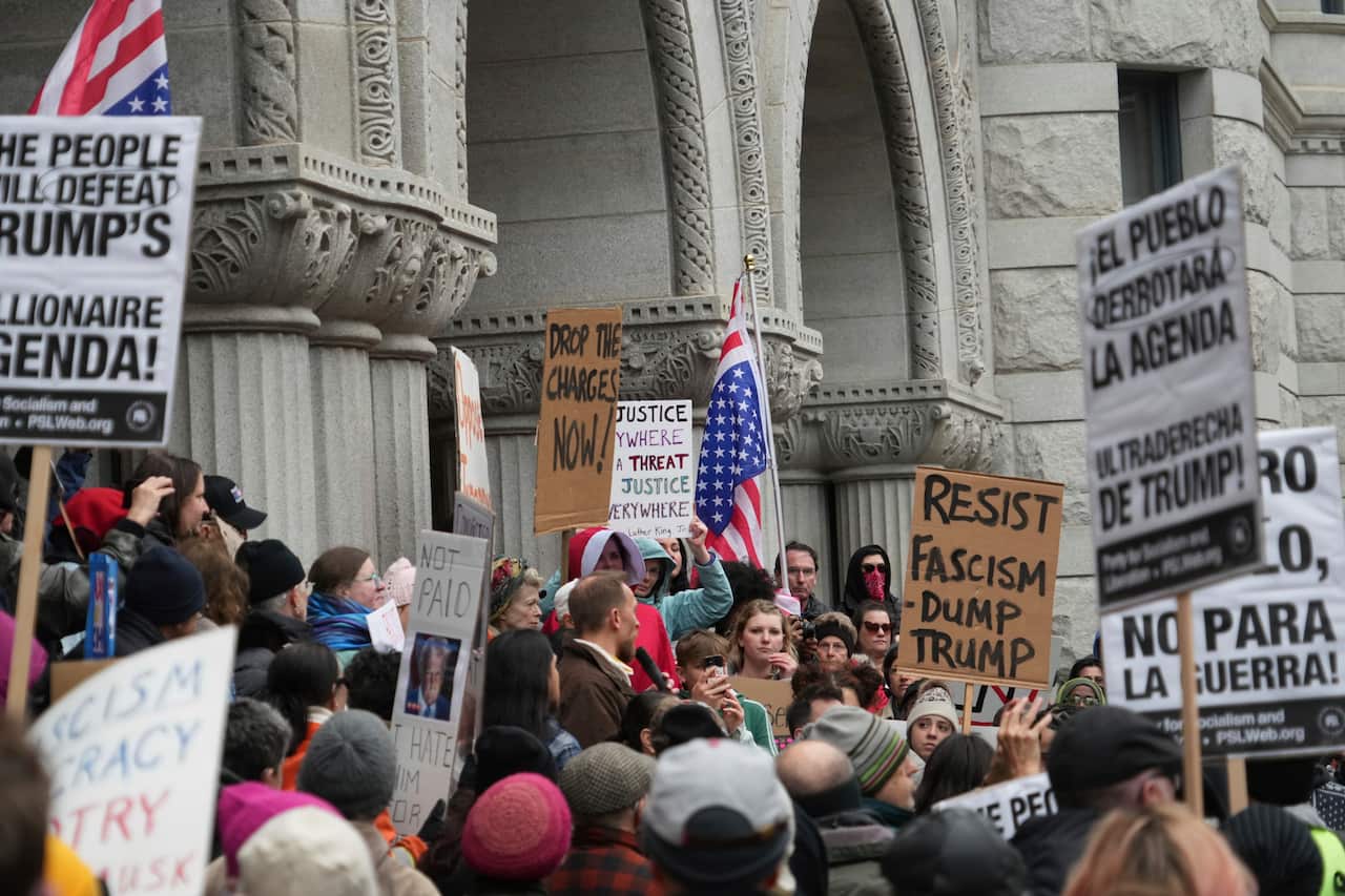 A large group of protesters outside a courthouse, many holding up signs.