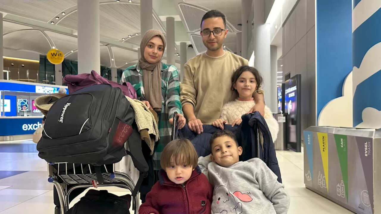 A family of five posing with their luggage in an airport