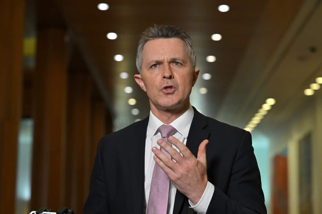 A man in a dark suit with a white shirt and pink tie 