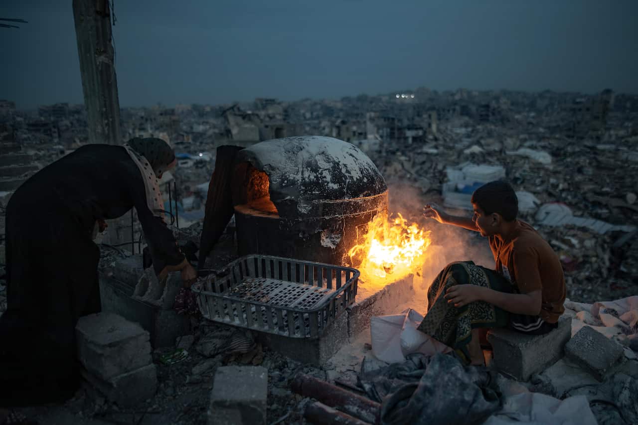 People sitting around a fire amid rubble.