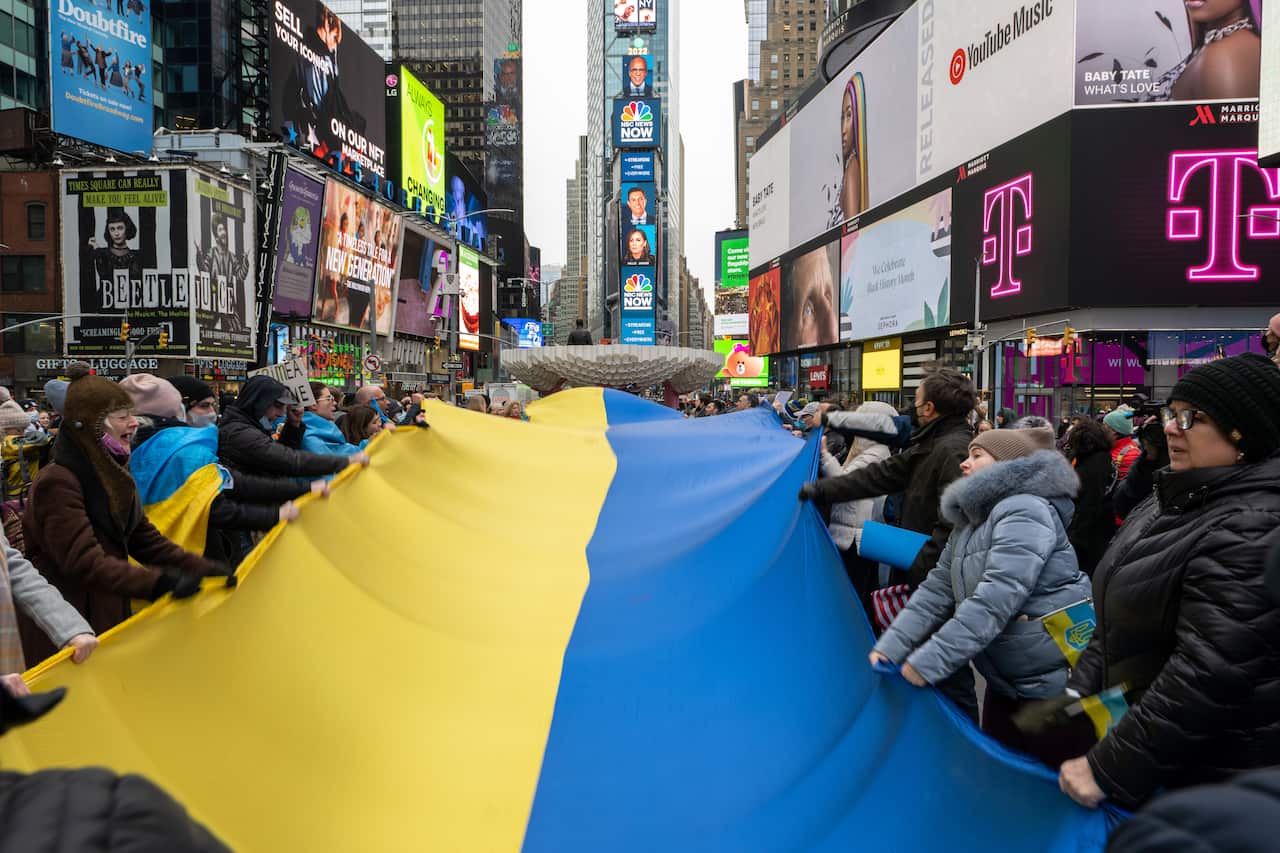 People holding a large Ukrainian flag gather for a "Stand With Ukraine" rally in Times Square, New York