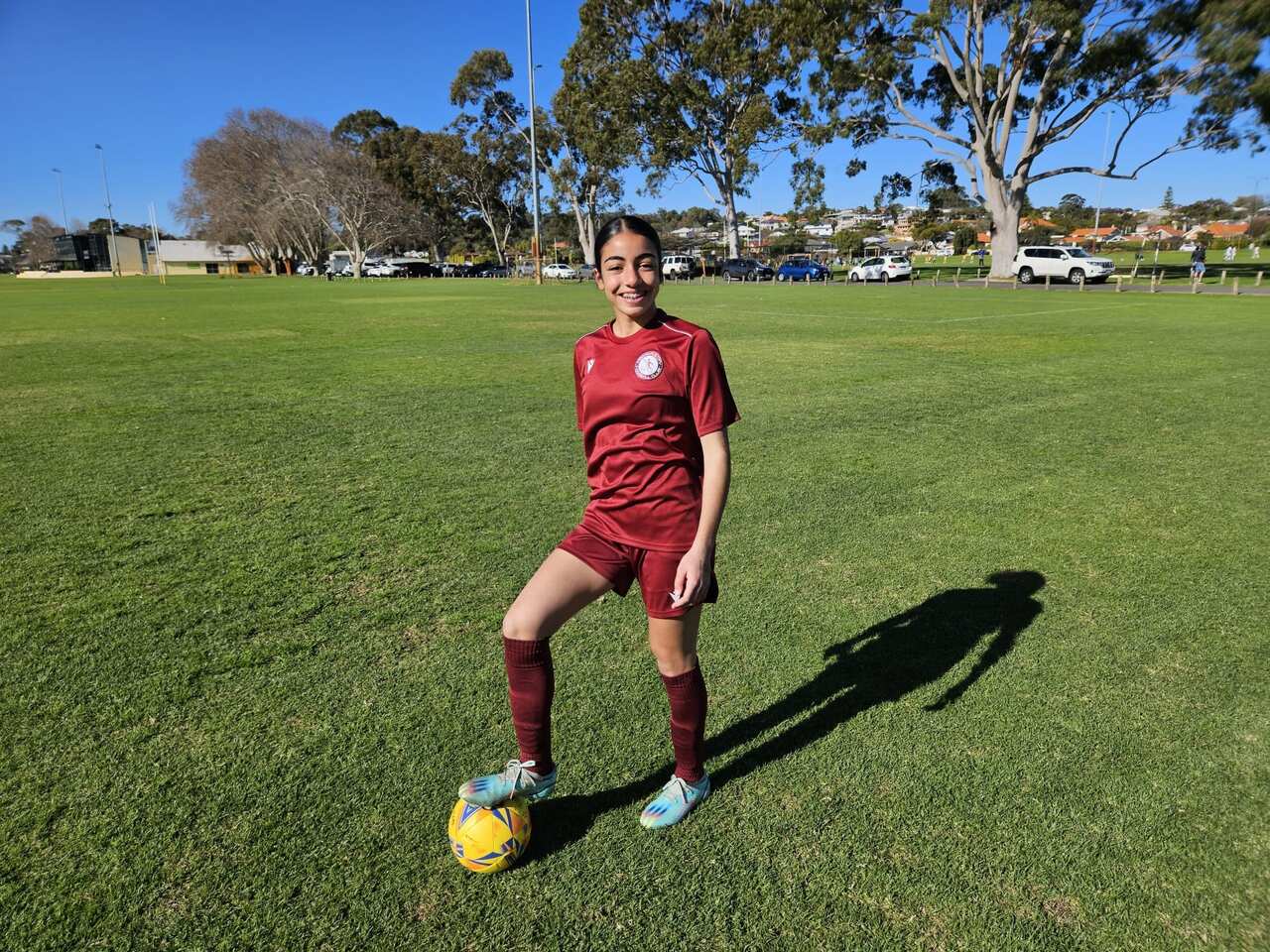 Sienna Pudia has her foot on the ball as she smiles at the camera. 