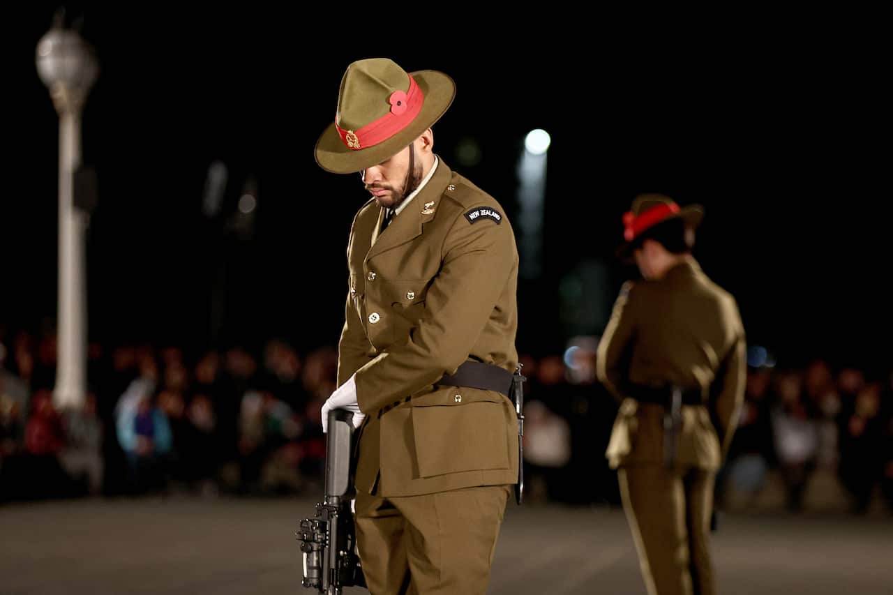 A man in uniform stands with his head down.
