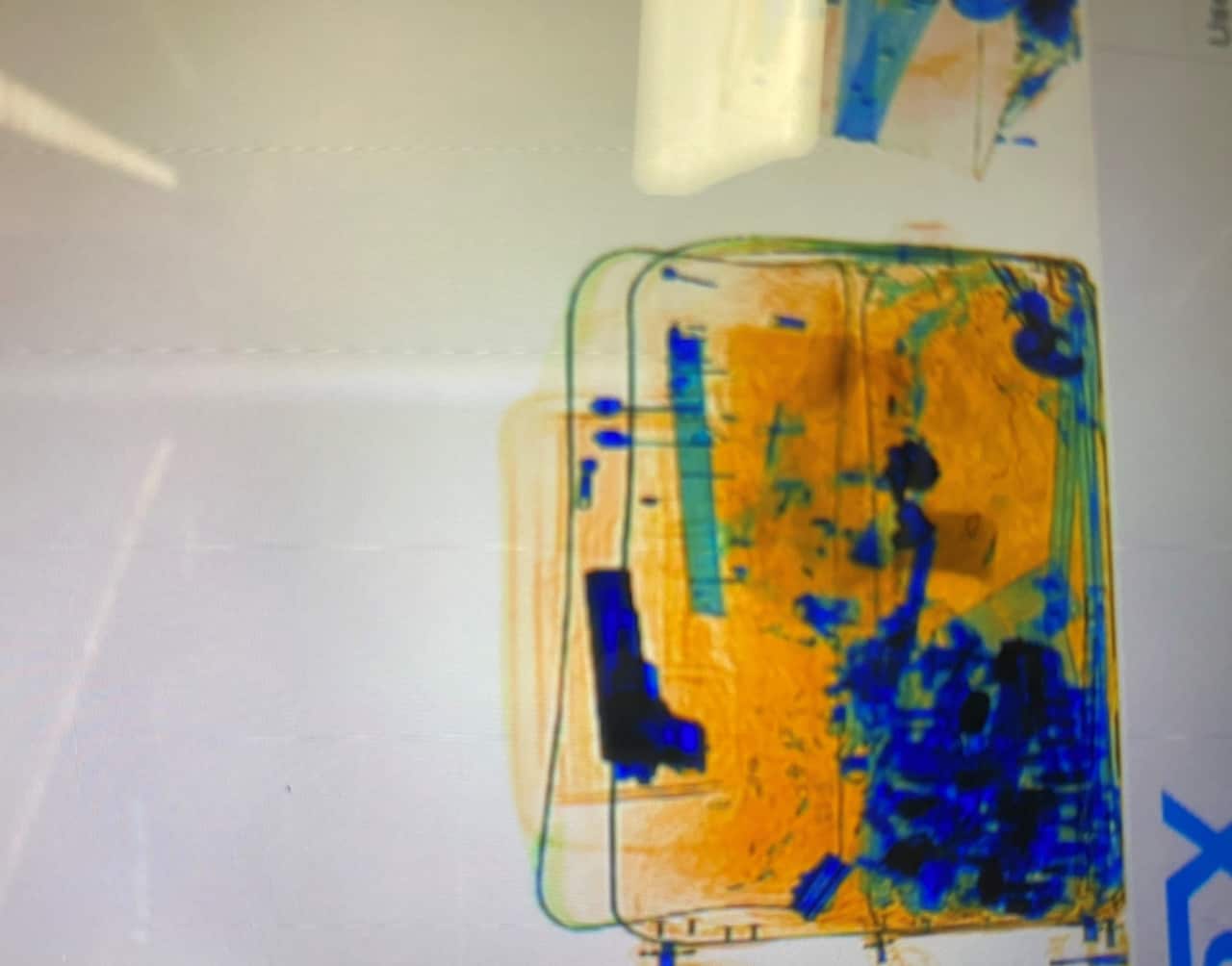 An x-ray of a suitcase showing an item the shape of a gun.
