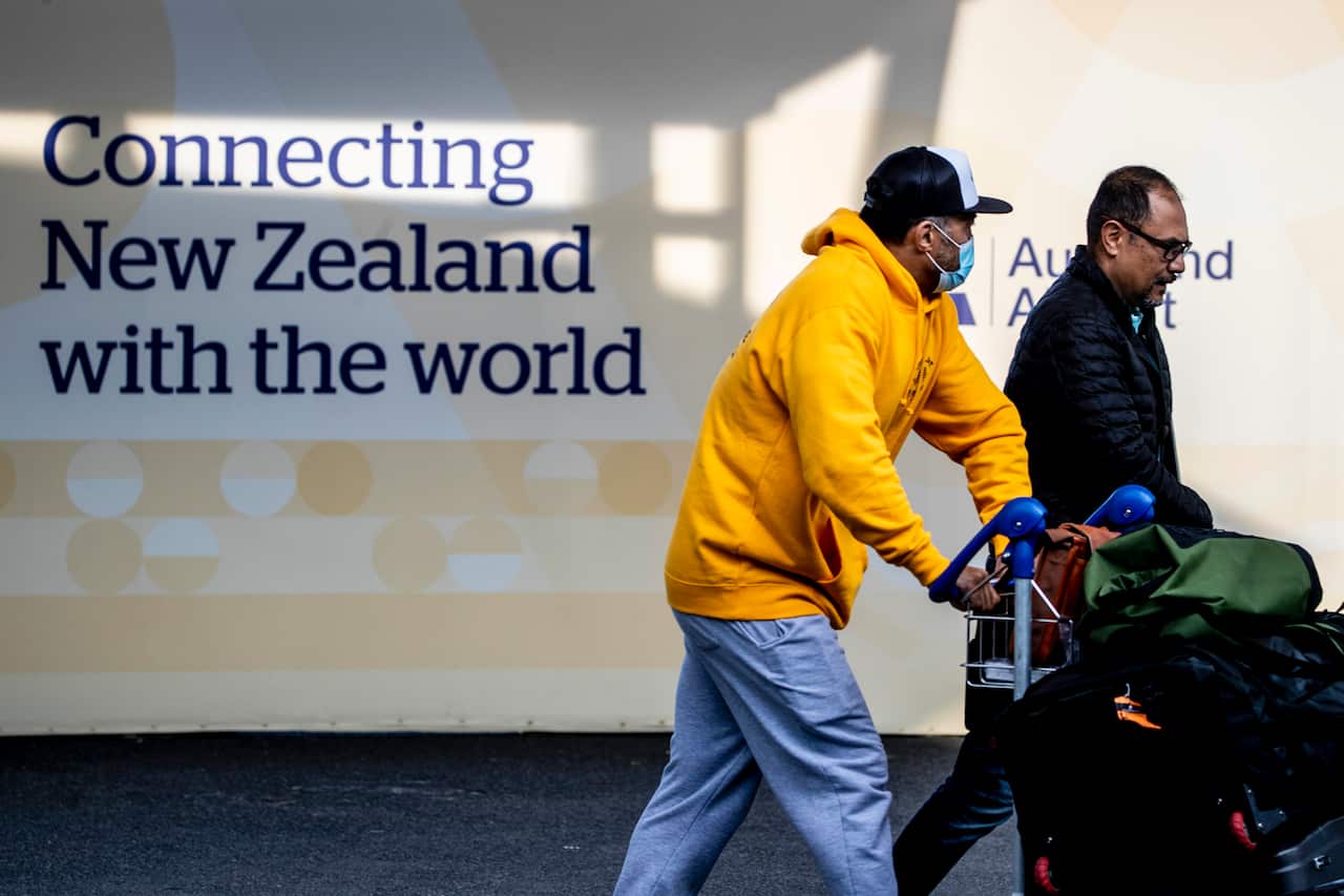 Two men pushing trolleys containing luggage at New Zealand airport