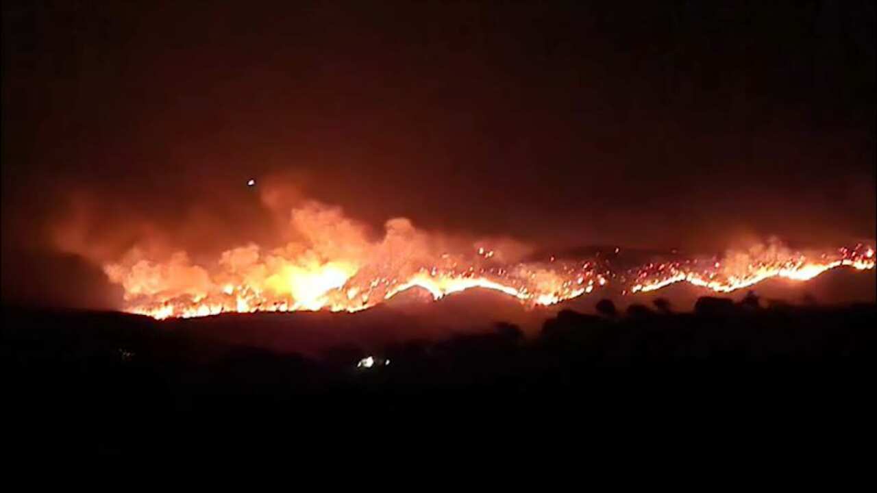 Fire burning along a ridegline at night.