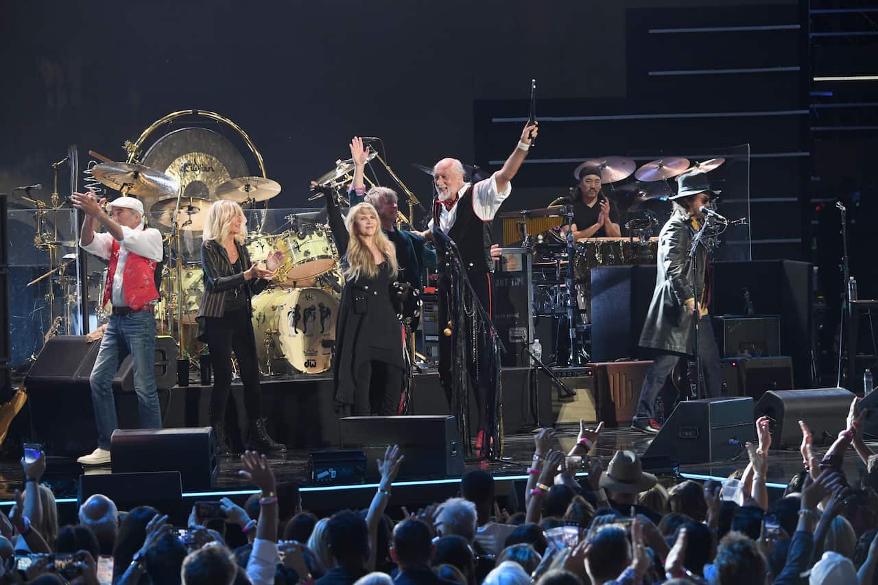 Members of the band Fleetwood Mac standing on stage in front of a crowd.