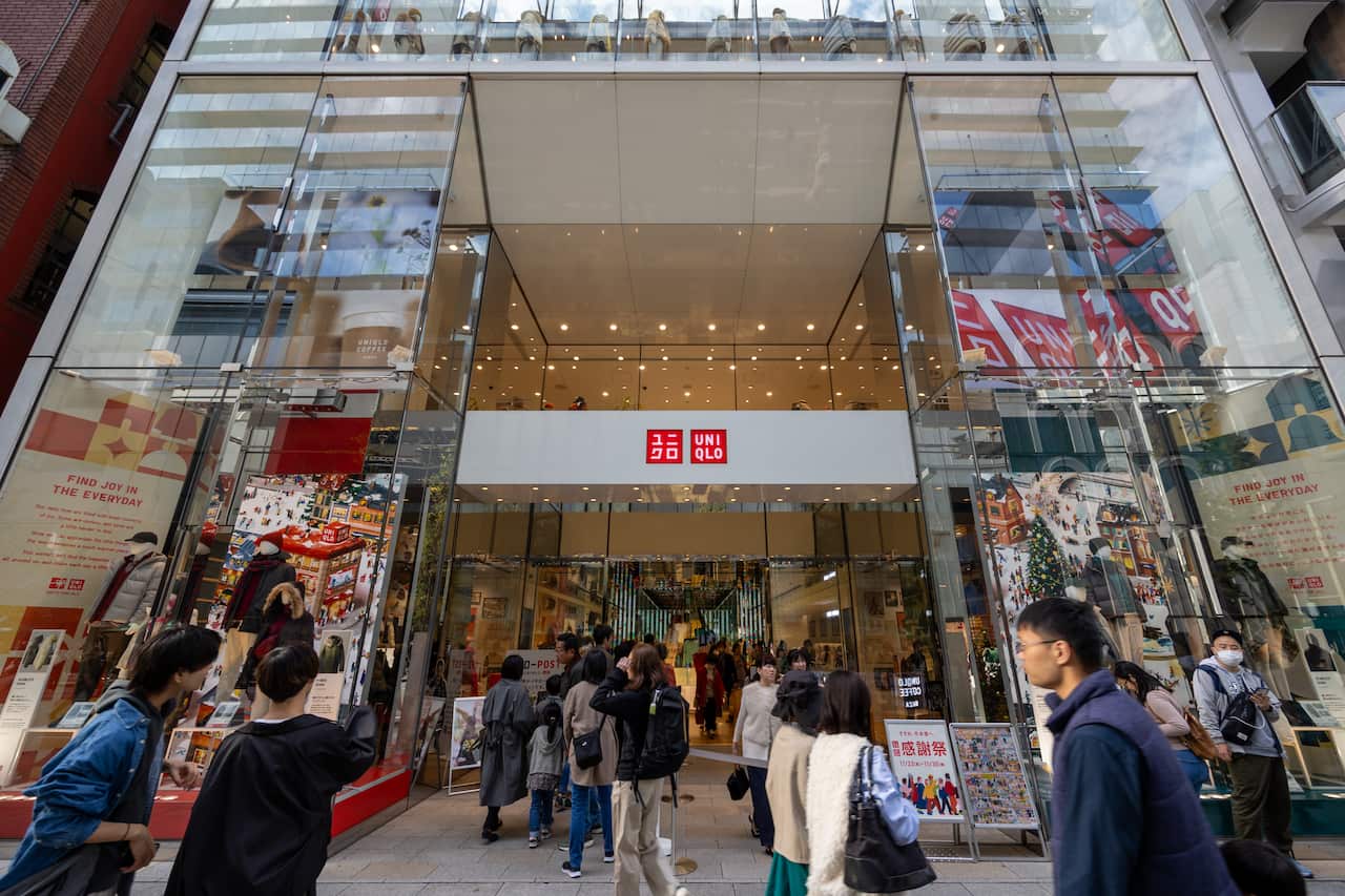 A large glass-fronted Uniqlo store with a group of people surrounding the entrance 