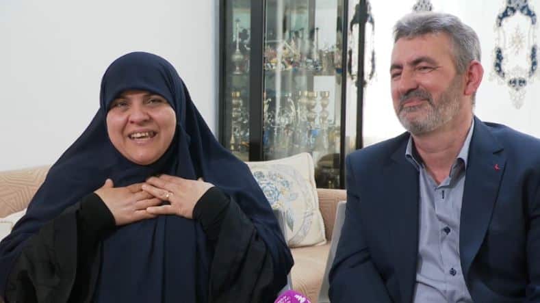 A couple who escaped war in Iraq sit next to each other in a living room. The woman, Amal holds her hands to her chest as she expresses her gratitude to the Australian government.