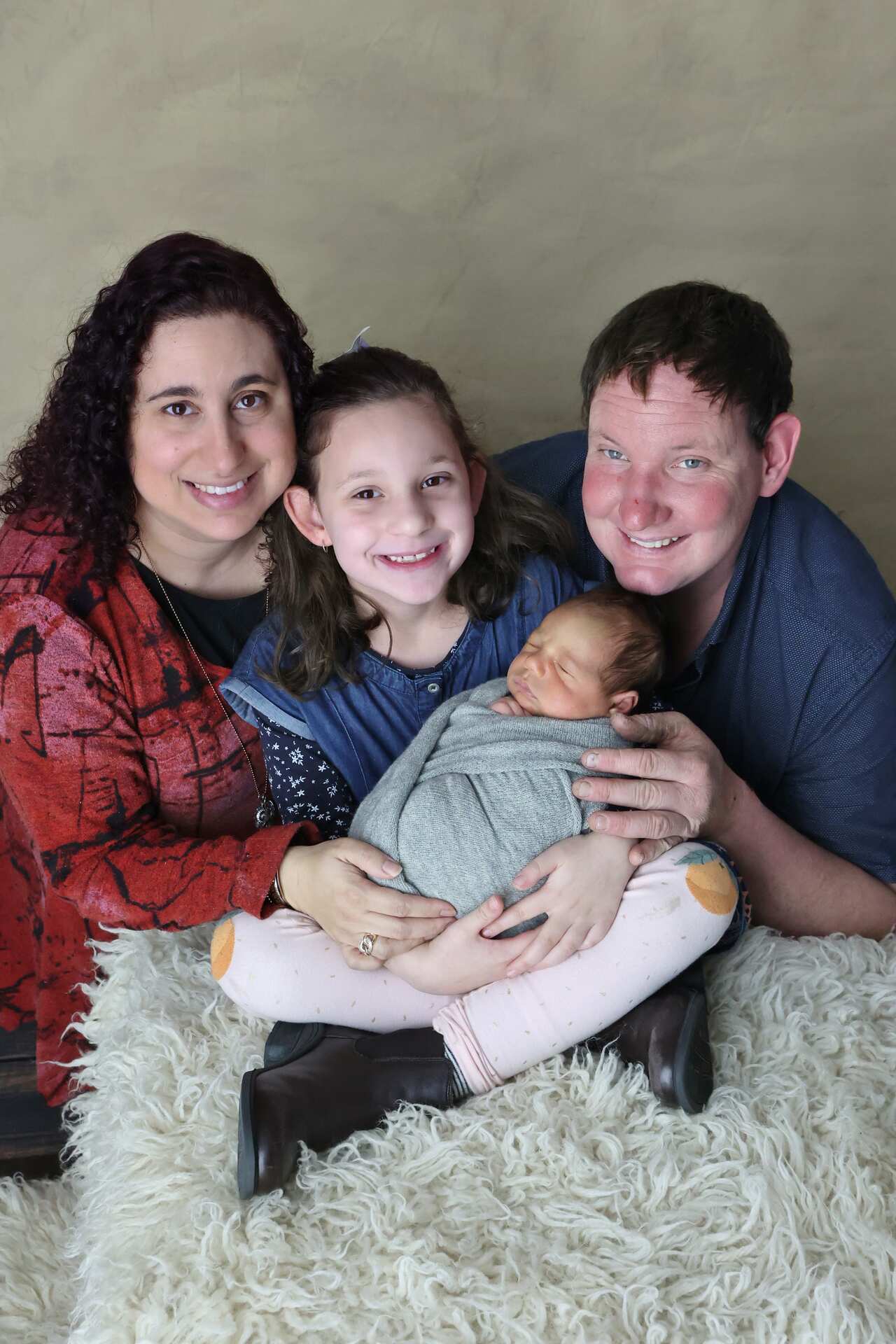 A mum, dad a young child and a newborn baby