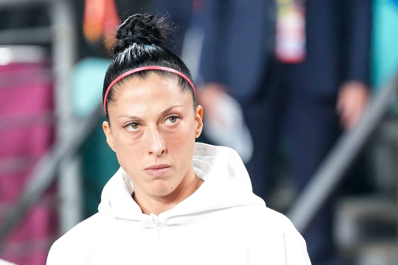 Spanish football player Jenni Hermoso in a white hooded sweatshirt and pink headband looking to the side of the camera