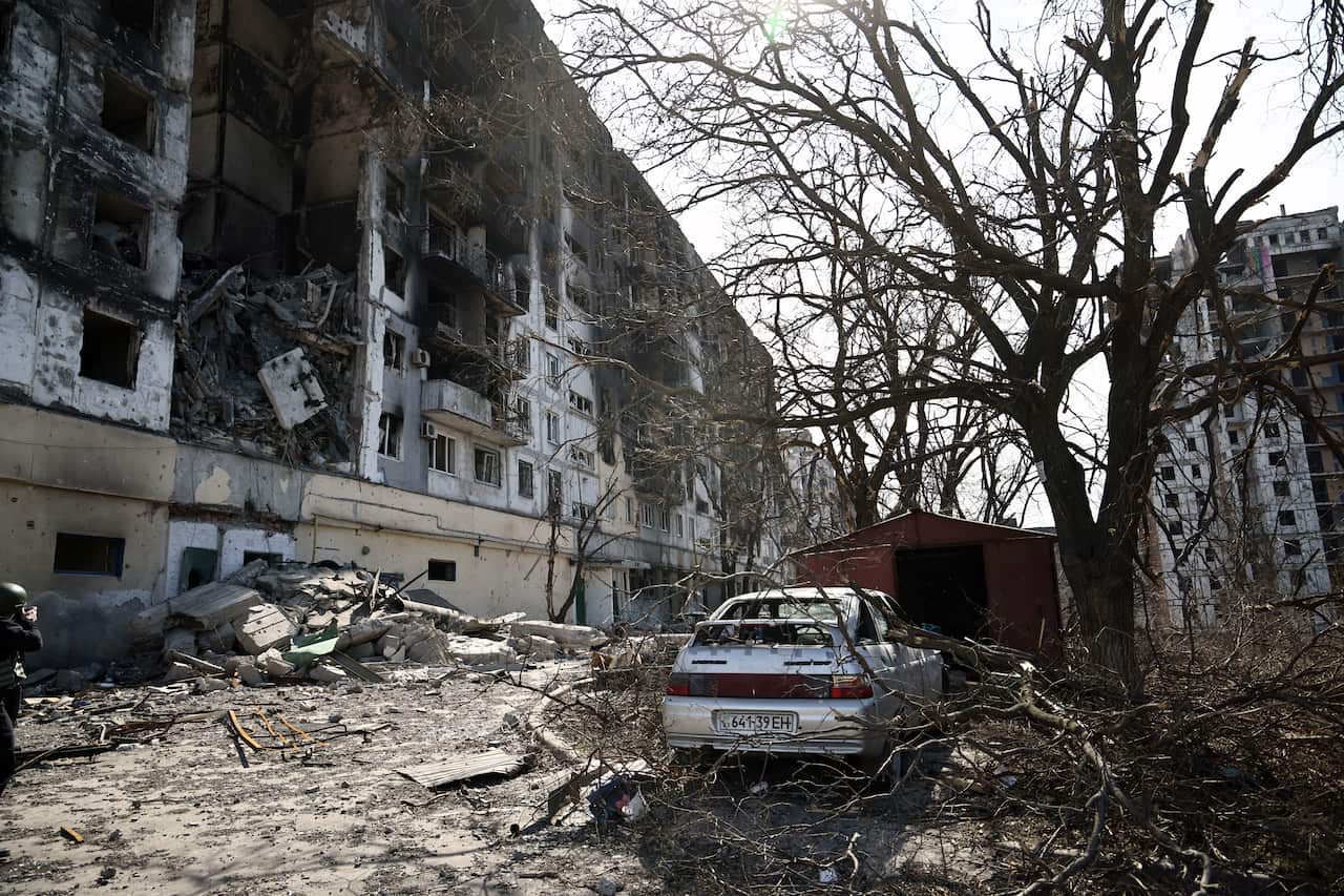 A destroyed building and damaged car is seen.