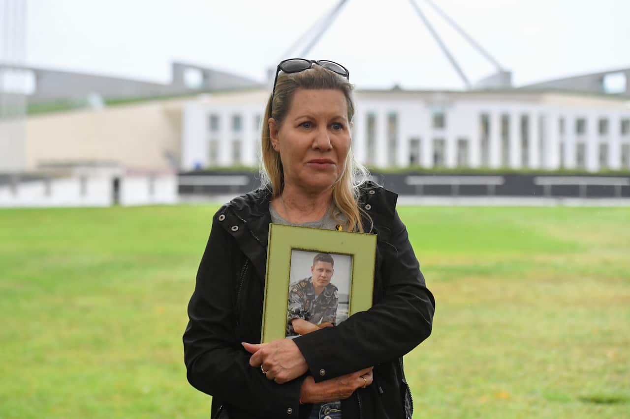 A woman holds a photo frame in her arms.