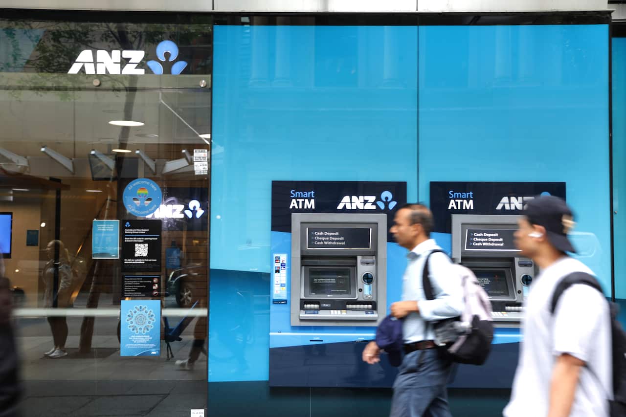 People on the street walk past a blue ANZ bank retail front.