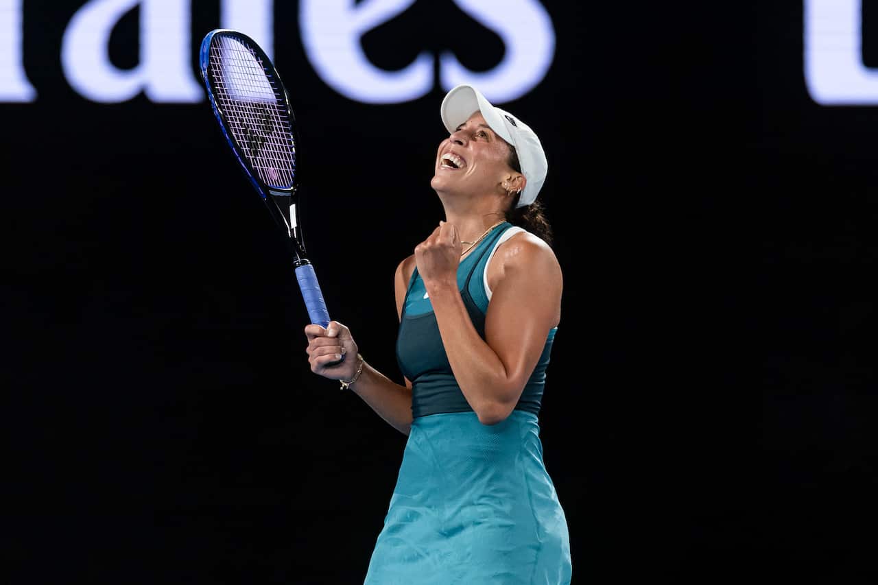 A woman smiling and holding a tennis racquet.
