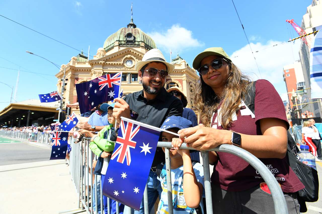 People carry Australian flags in front of Flinders St Station. 