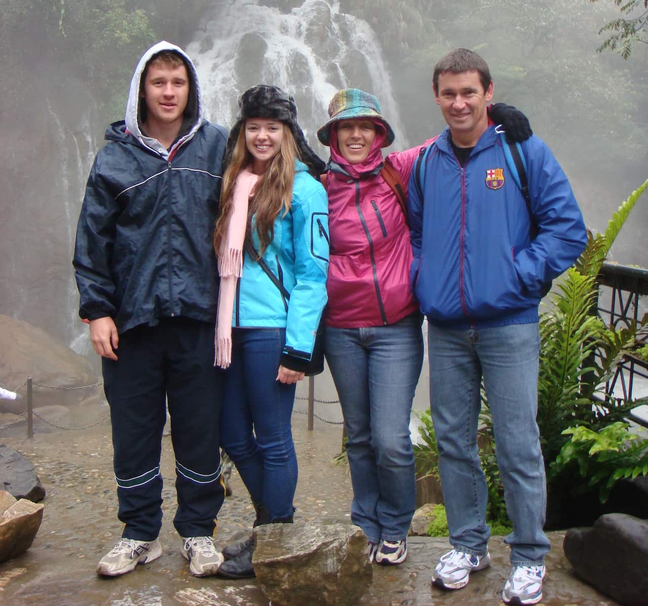 Four people standing in front of a waterfall 