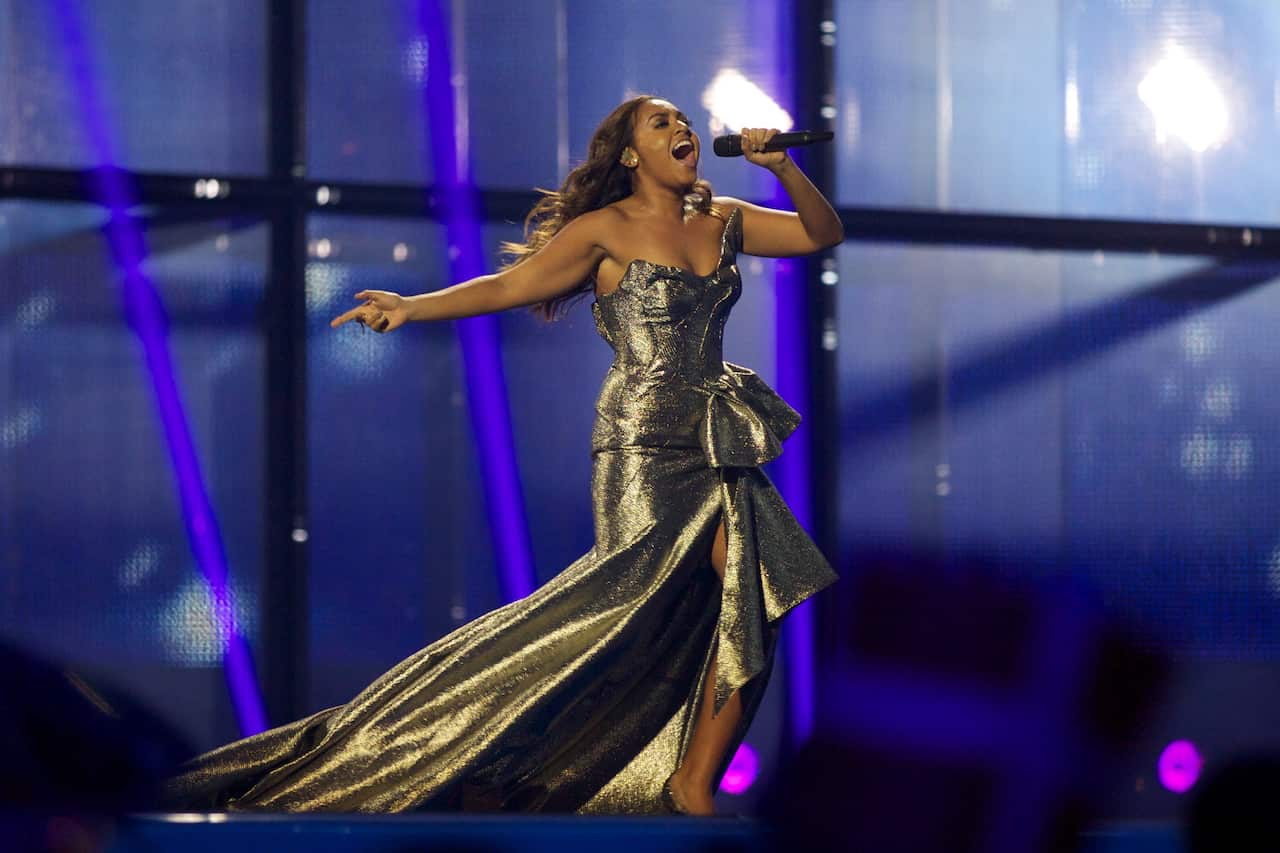 Woman in gold dress singing into microphone