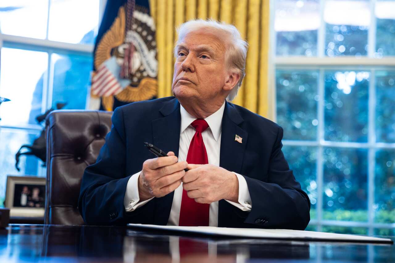 Donald Trump holds a pen as he lifts his head up defiantly.