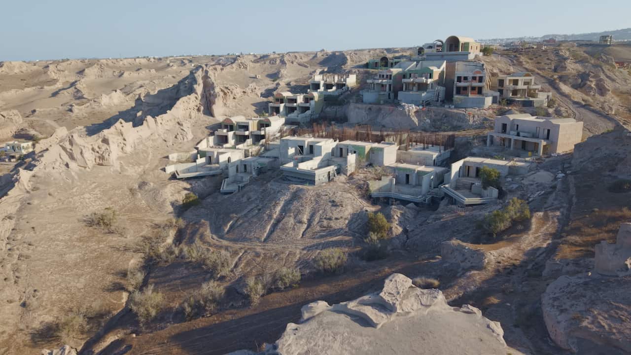 White buildings being built into a rocky cliffside. 