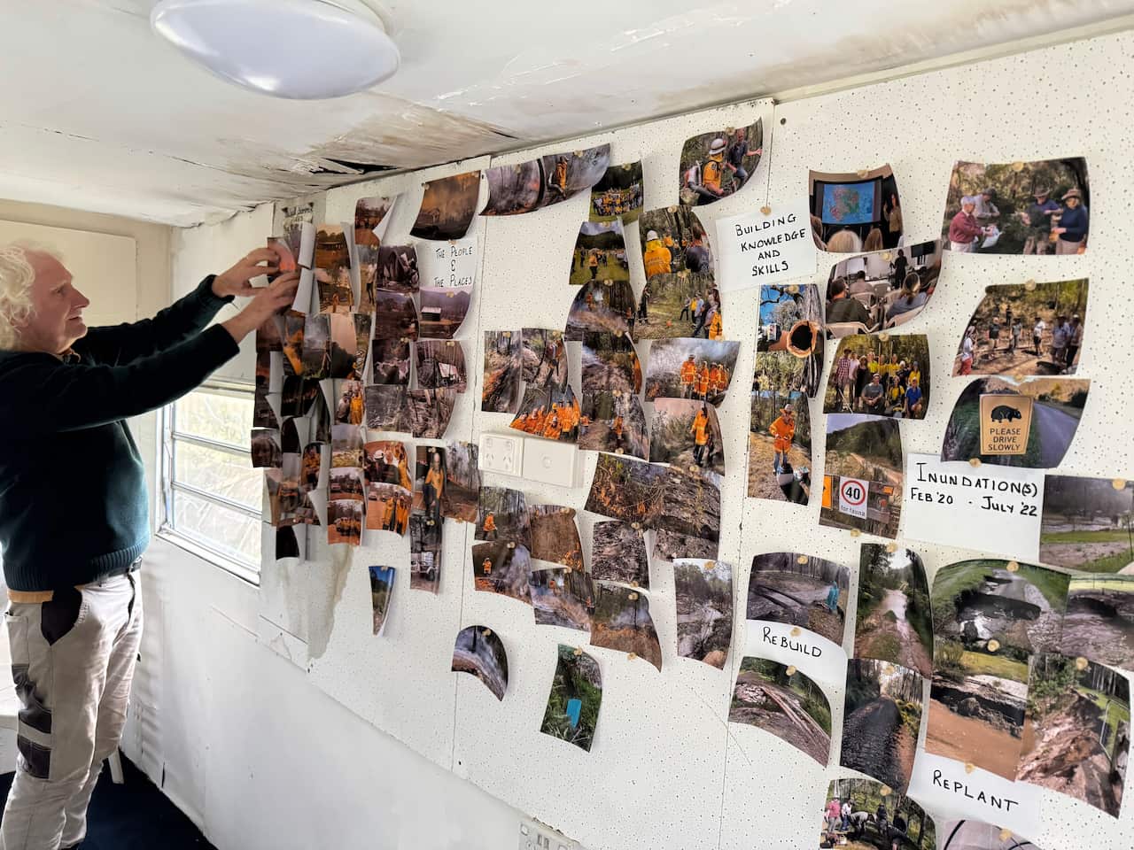 A man sticks a photo on to a wall covered in printed photos